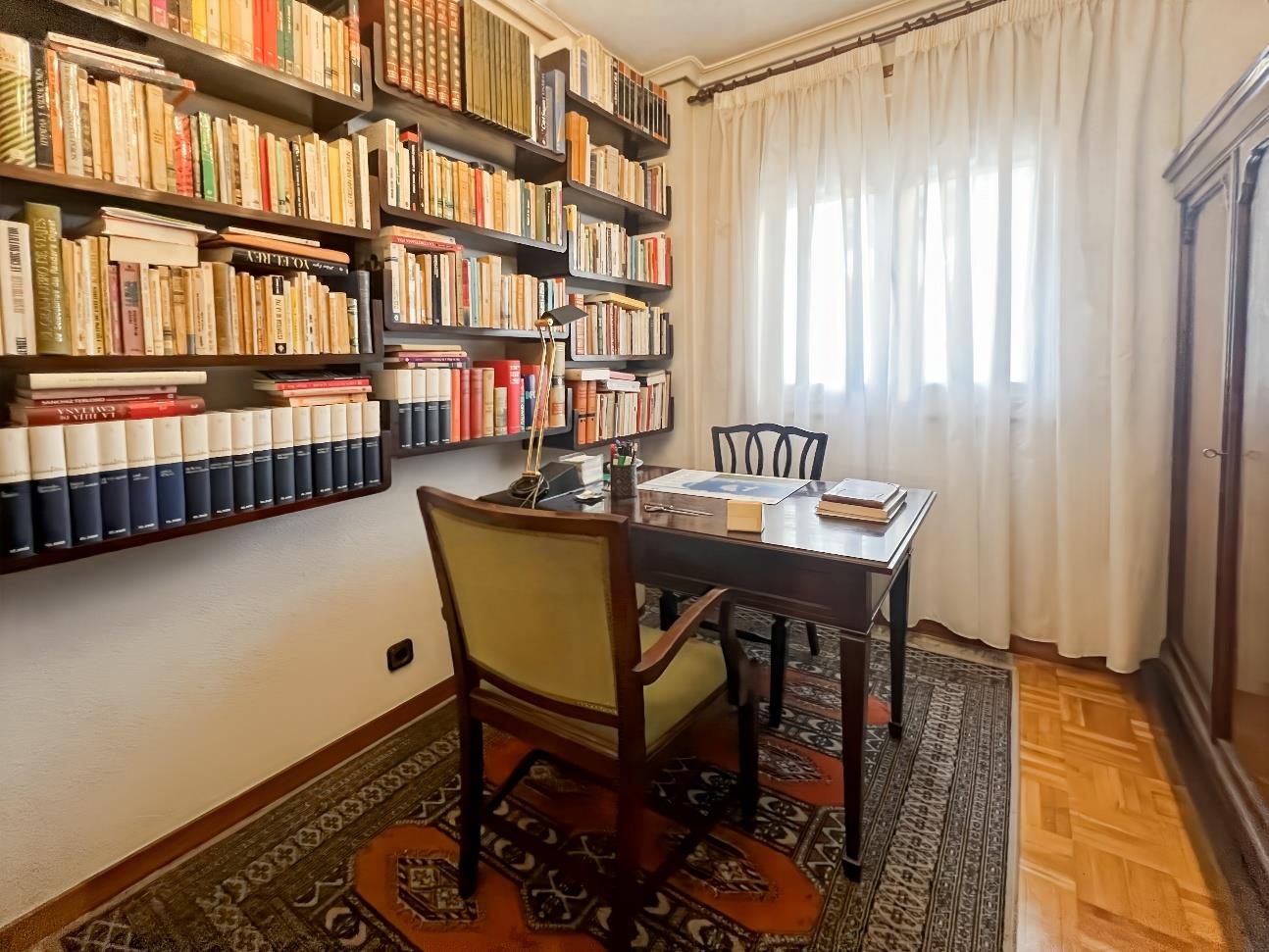 Despacho clásico con biblioteca repleta de libros, escritorio de madera y alfombra persa