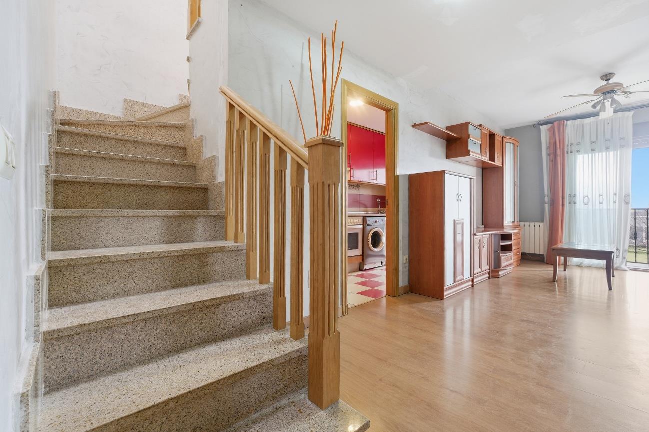 Recibidor con escalera de granito y vista a la cocina abierta con muebles de madera